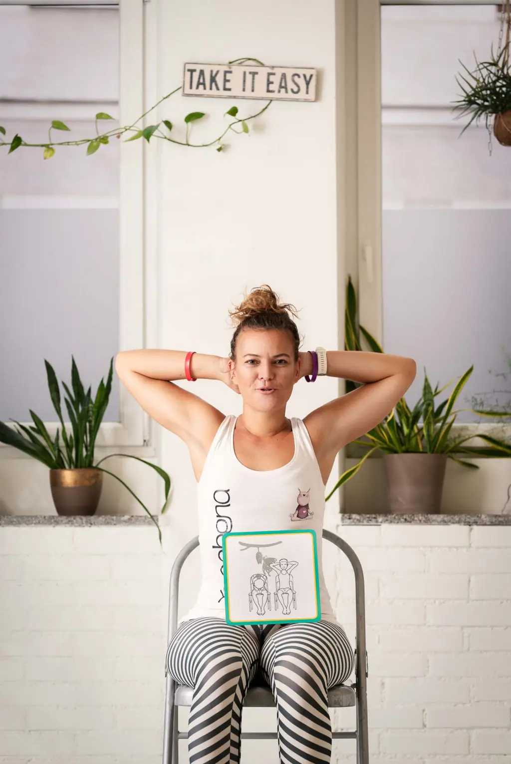 Monika sitzt auf einem Stuhl mit hinter ihrem Kopf verschränkten Armen